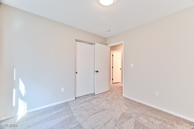 unfurnished bedroom with light carpet and a closet