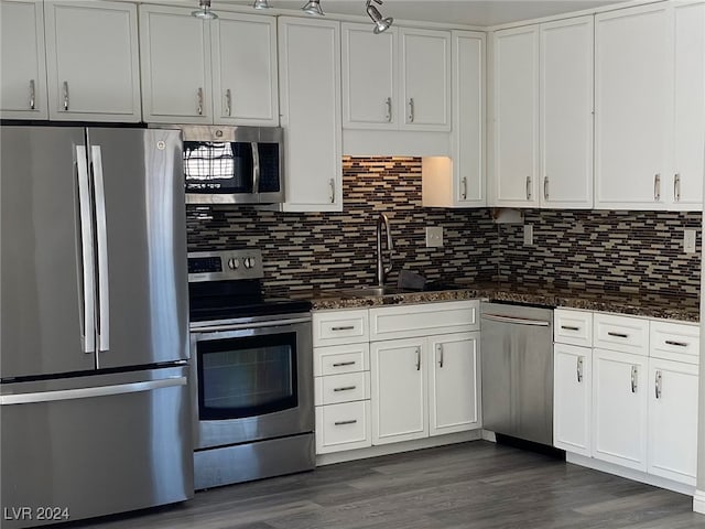 kitchen with appliances with stainless steel finishes, dark hardwood / wood-style flooring, sink, dark stone countertops, and white cabinets