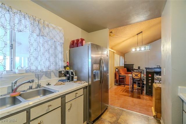 kitchen featuring sink, pendant lighting, a textured ceiling, and stainless steel fridge with ice dispenser