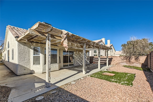 rear view of property featuring a pergola and a patio