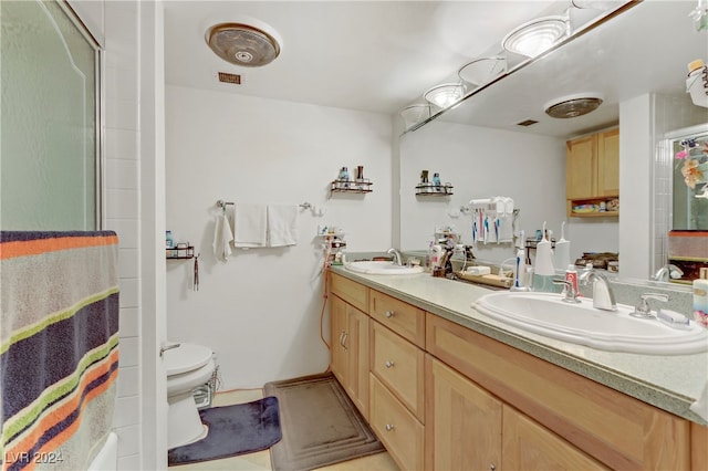 bathroom featuring vanity, toilet, and a shower with shower door