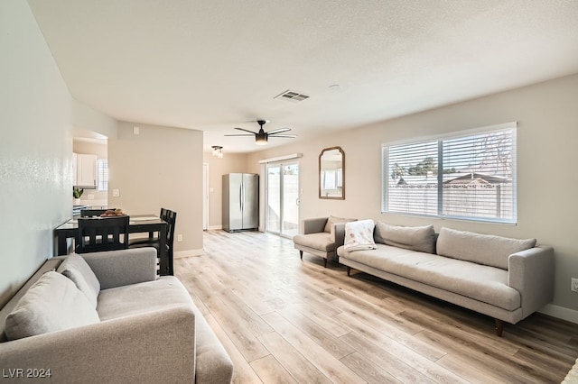 living room with a wealth of natural light, light hardwood / wood-style flooring, and ceiling fan