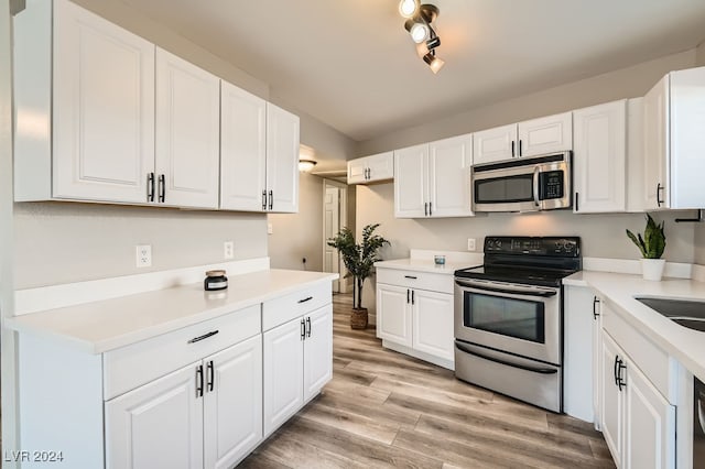 kitchen with white cabinets, track lighting, appliances with stainless steel finishes, and light hardwood / wood-style flooring