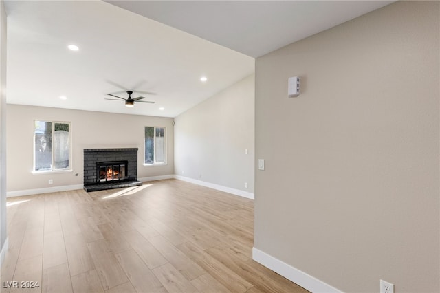 unfurnished living room with plenty of natural light, light hardwood / wood-style floors, ceiling fan, and a brick fireplace