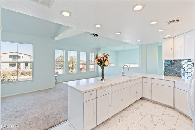 kitchen with white cabinetry, sink, tasteful backsplash, kitchen peninsula, and light carpet