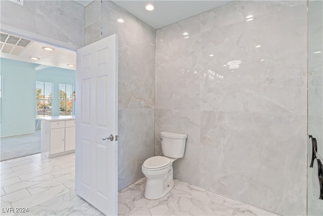 bathroom with vanity, toilet, and tile walls