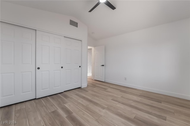 unfurnished bedroom with ceiling fan, a closet, lofted ceiling, and light wood-type flooring