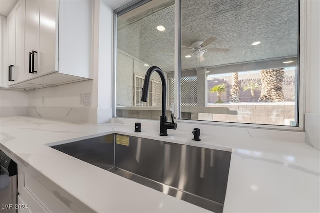 kitchen featuring white cabinetry, sink, dishwasher, light stone counters, and a textured ceiling