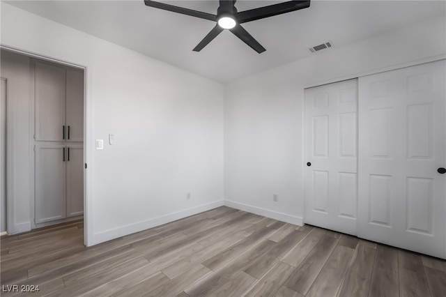 unfurnished bedroom featuring ceiling fan, light hardwood / wood-style floors, and a closet