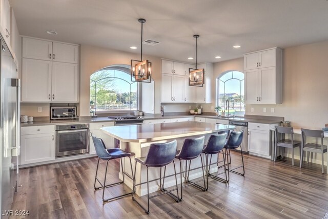 kitchen featuring decorative light fixtures, dark hardwood / wood-style flooring, white cabinetry, and appliances with stainless steel finishes