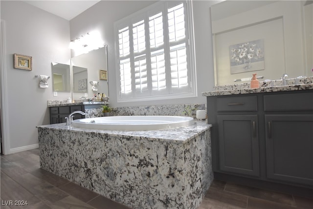 bathroom featuring tiled bath, hardwood / wood-style floors, and vanity