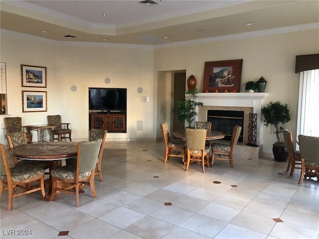 dining area featuring ornamental molding, a fireplace, a tray ceiling, and light tile patterned floors