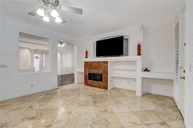 unfurnished living room with ceiling fan and a tiled fireplace