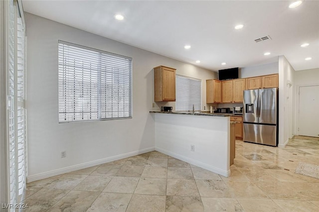 kitchen featuring dark stone countertops, kitchen peninsula, and stainless steel fridge with ice dispenser