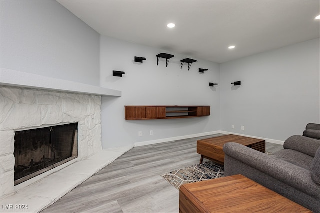 living room featuring light wood-type flooring and a stone fireplace