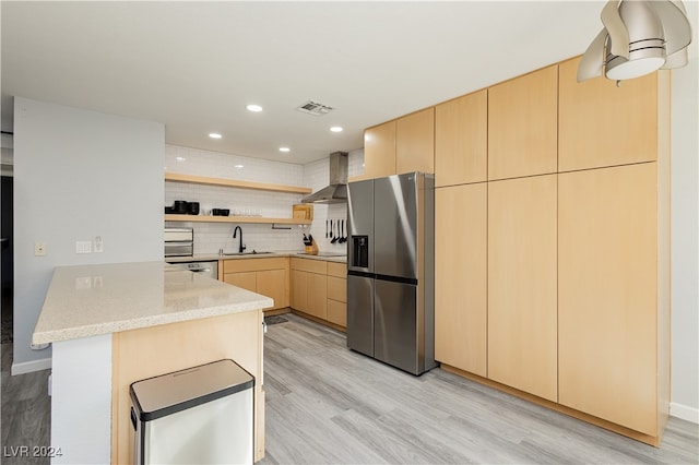 kitchen featuring sink, wall chimney exhaust hood, light brown cabinetry, appliances with stainless steel finishes, and kitchen peninsula