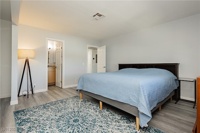 bedroom with light wood-type flooring and ensuite bathroom