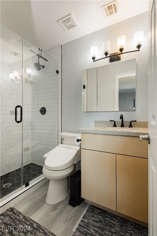 bathroom featuring walk in shower, hardwood / wood-style floors, a textured ceiling, toilet, and vanity