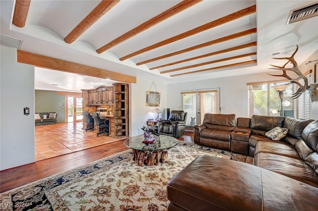 living room with beam ceiling, plenty of natural light, and light hardwood / wood-style floors