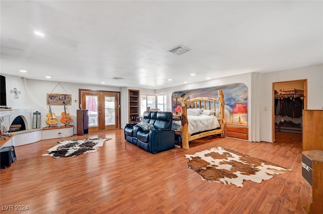 bedroom with a spacious closet, french doors, and light hardwood / wood-style flooring