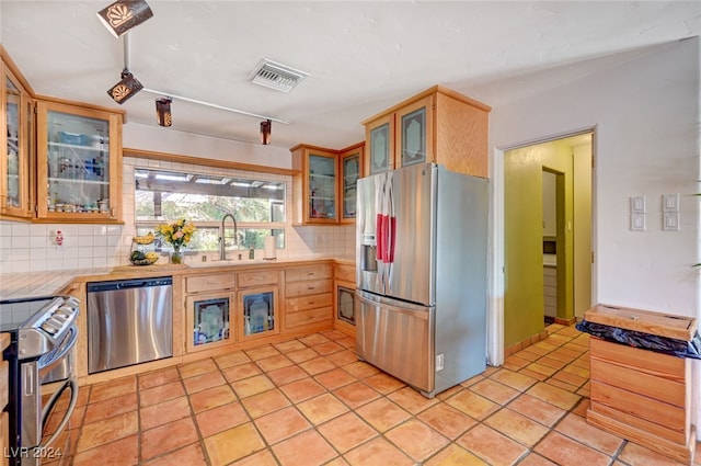 kitchen featuring tasteful backsplash, sink, light tile patterned floors, and stainless steel appliances