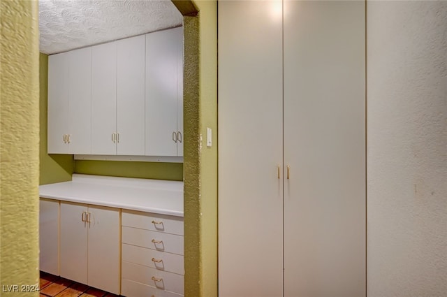 interior space featuring white cabinetry, a textured ceiling, and light wood-type flooring