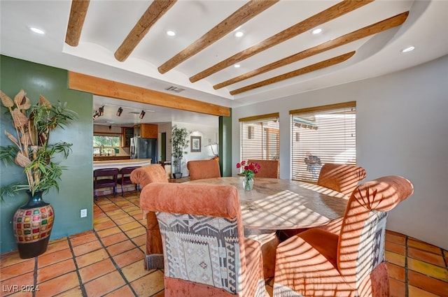 tiled dining space featuring beam ceiling