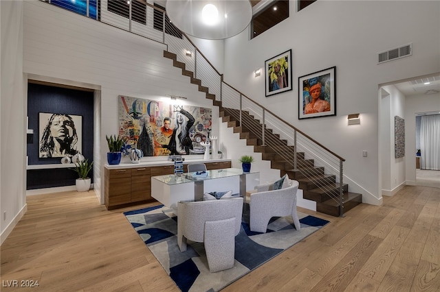 dining area featuring light hardwood / wood-style floors and a towering ceiling