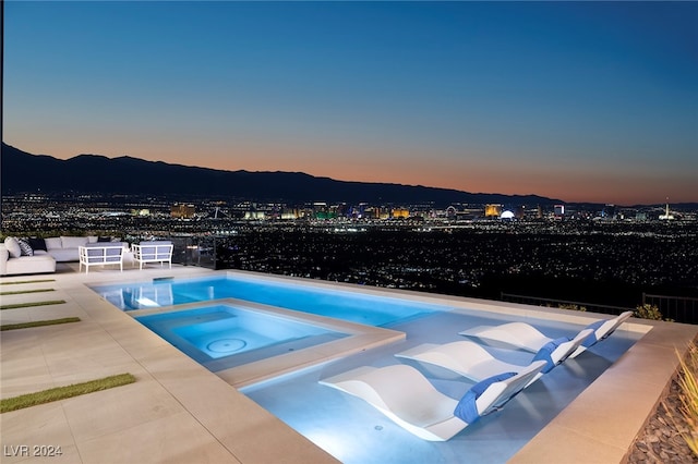 pool at dusk with a mountain view, an outdoor hangout area, an in ground hot tub, and a patio