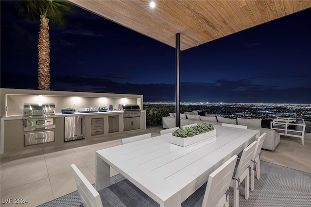 patio at night featuring a grill and exterior kitchen