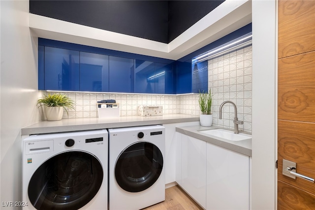 clothes washing area with independent washer and dryer, sink, cabinets, and light wood-type flooring