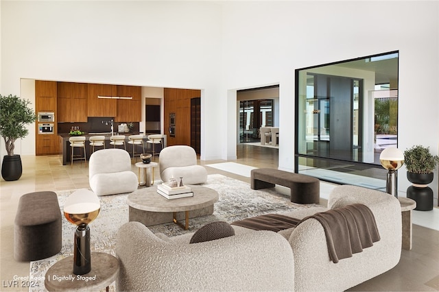 living room with sink, a towering ceiling, and light tile patterned floors