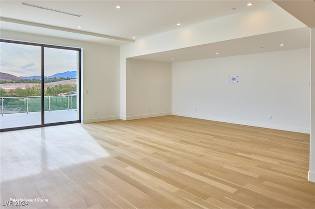 unfurnished room with a mountain view and light wood-type flooring