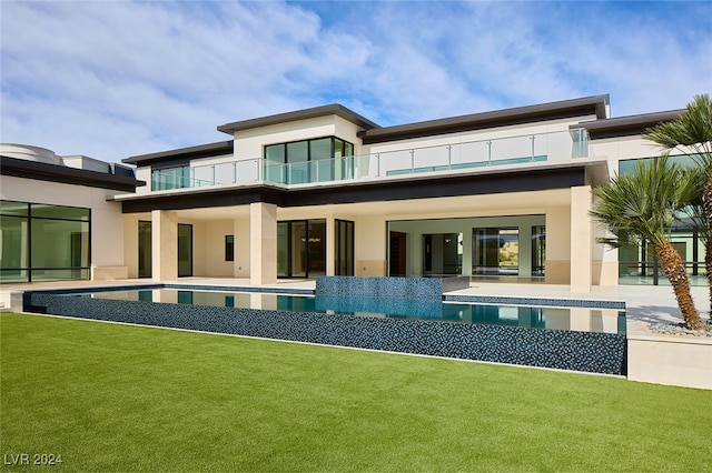 rear view of property with a yard and a balcony