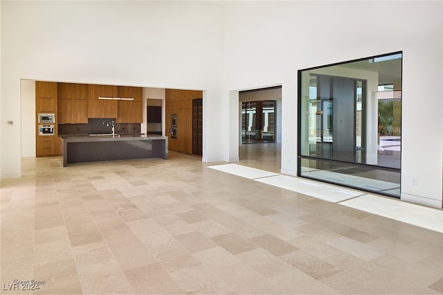 unfurnished living room with a high ceiling and sink