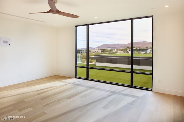 spare room with a mountain view, light hardwood / wood-style floors, and ceiling fan