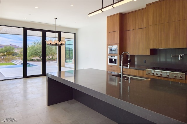 kitchen featuring pendant lighting, backsplash, sink, stainless steel appliances, and a chandelier