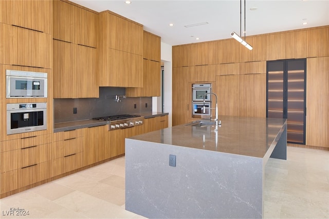 kitchen with tasteful backsplash, stainless steel appliances, sink, decorative light fixtures, and a large island