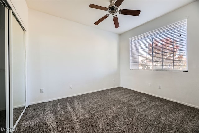 spare room with ceiling fan and dark colored carpet