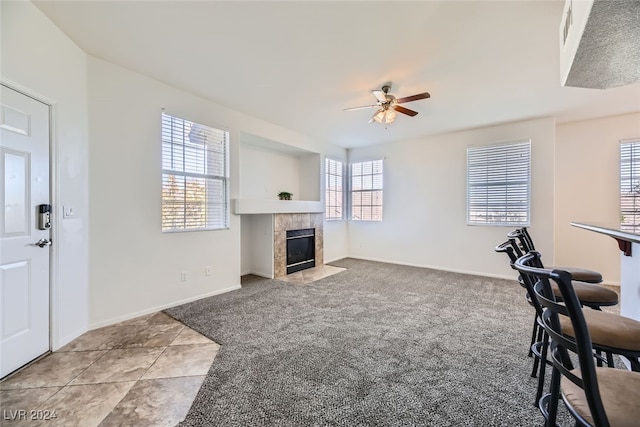 interior space with plenty of natural light, ceiling fan, light carpet, and a tile fireplace