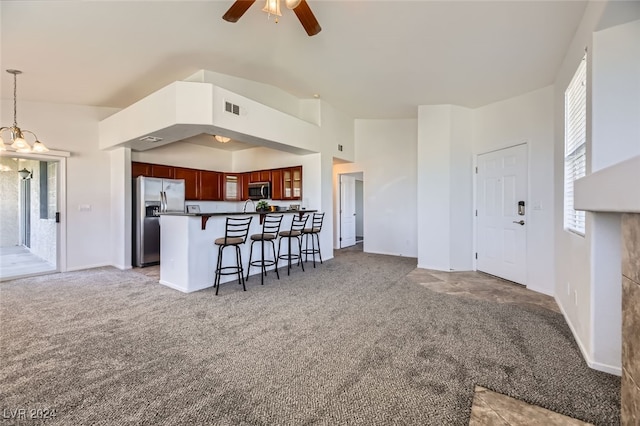 kitchen with a breakfast bar, ceiling fan with notable chandelier, carpet flooring, decorative light fixtures, and stainless steel appliances