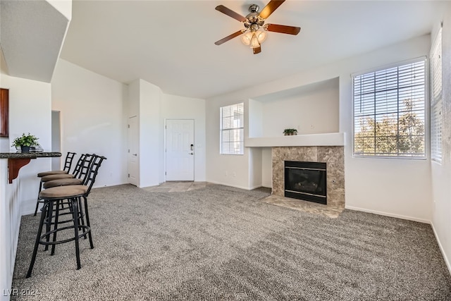 carpeted living room featuring a tile fireplace and ceiling fan