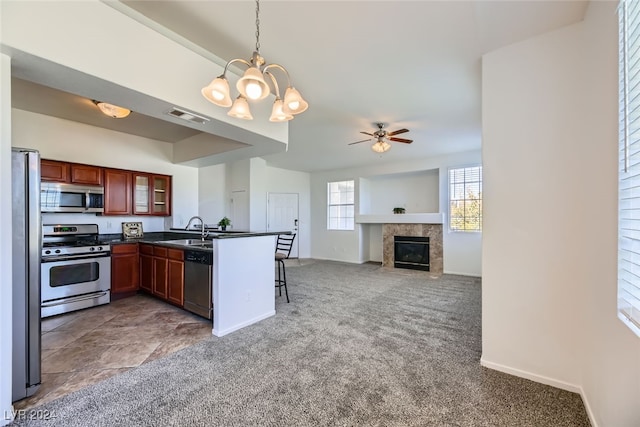 kitchen featuring ceiling fan with notable chandelier, sink, decorative light fixtures, kitchen peninsula, and stainless steel appliances