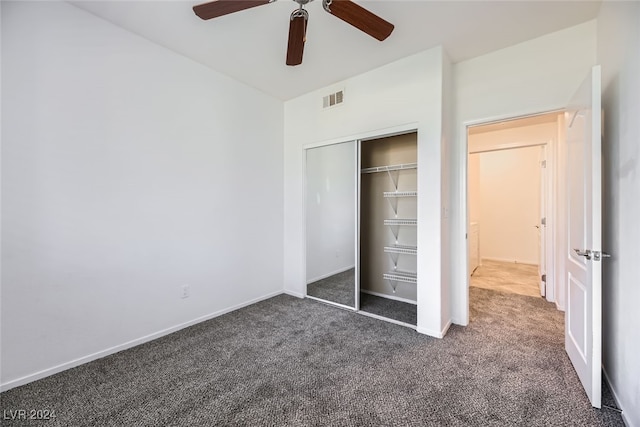 unfurnished bedroom with dark colored carpet, ceiling fan, and a closet