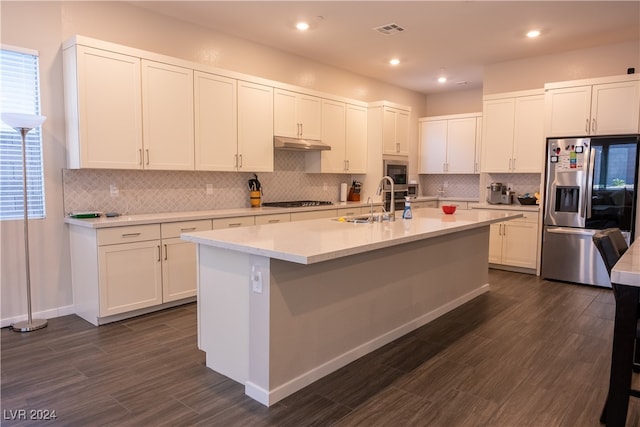 kitchen with tasteful backsplash, dark hardwood / wood-style floors, a center island with sink, white cabinets, and appliances with stainless steel finishes