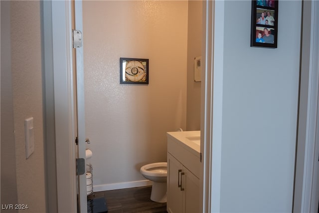 bathroom with hardwood / wood-style flooring, vanity, and toilet