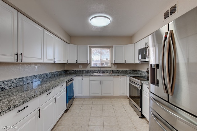 kitchen featuring white cabinets, dark stone countertops, sink, and stainless steel appliances