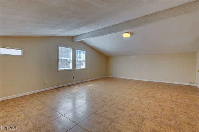 bonus room featuring a textured ceiling, vaulted ceiling with beams, and light tile patterned floors