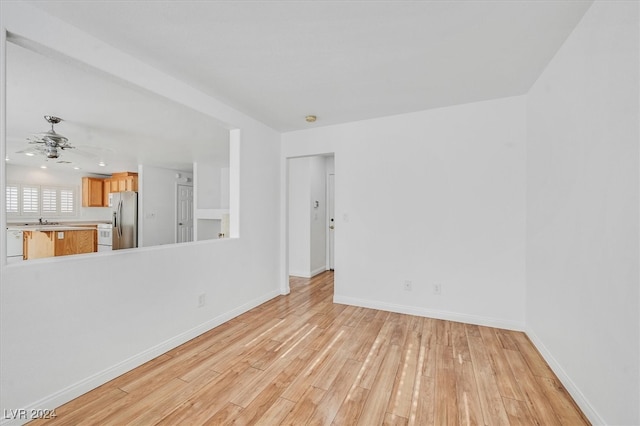 unfurnished living room with ceiling fan, sink, and light wood-type flooring