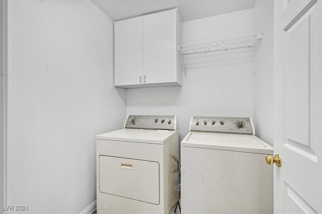 clothes washing area with cabinets and separate washer and dryer